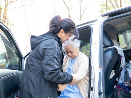 A lady helps her mum into a car