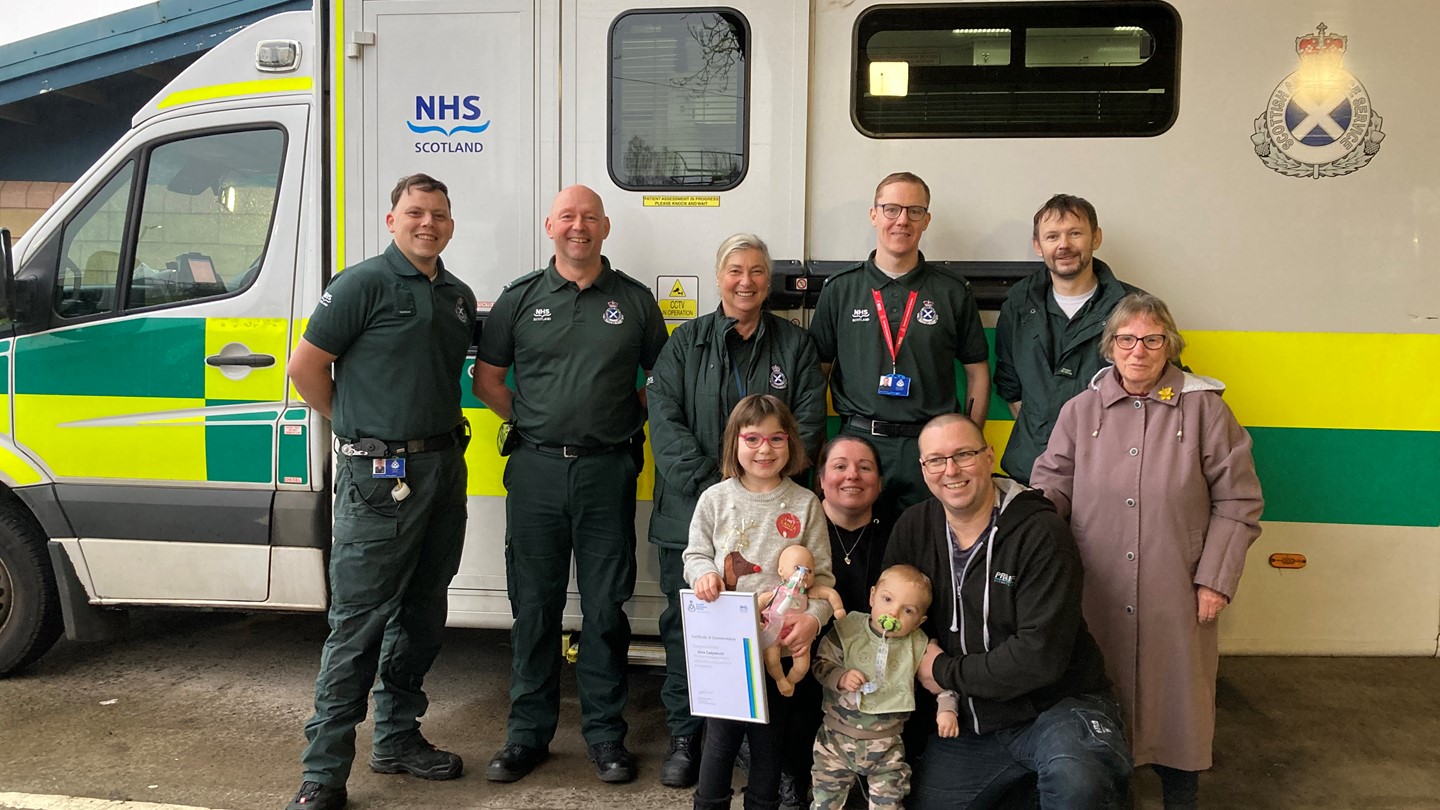 Alice with family and certificate at Paisley station with other ambulance service staff