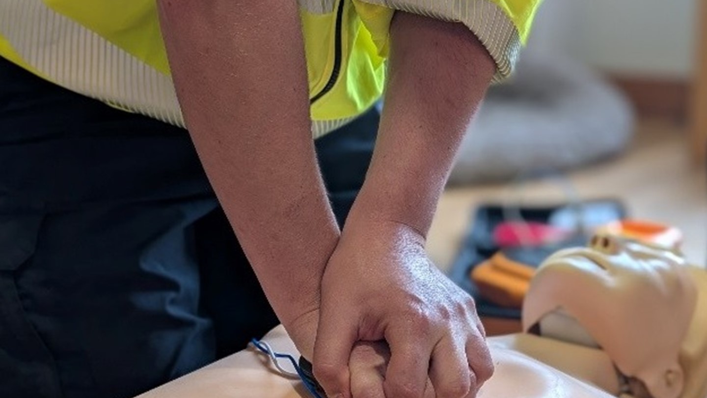 Two arms performing CPR on a CPR dummy.