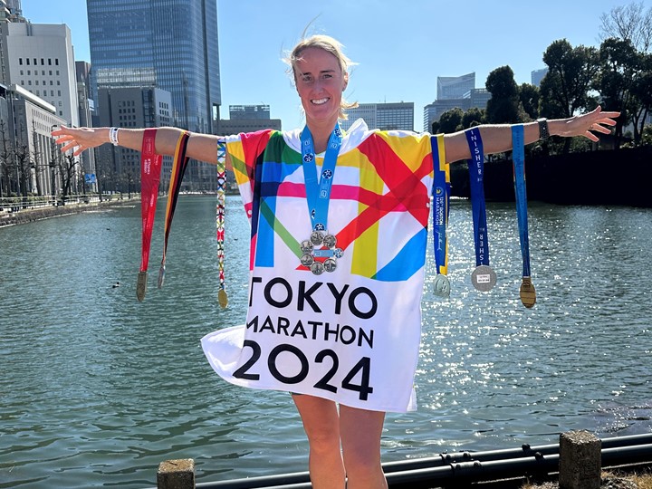 Lyn stands in front of some water showng of her medals