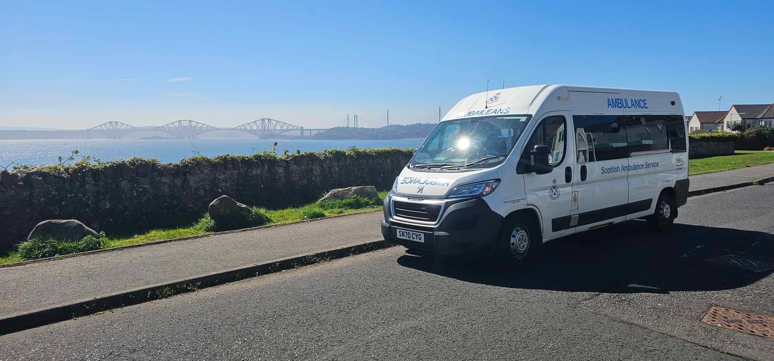 A Patient Transport ambulance on a road with the sea behind