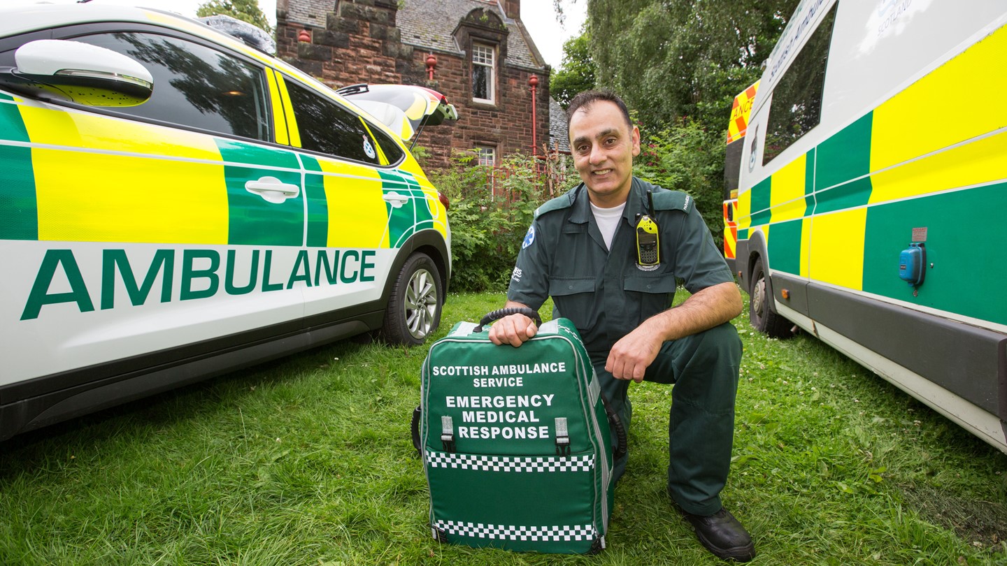 A Paramedic kneels between two ambulance vehicles