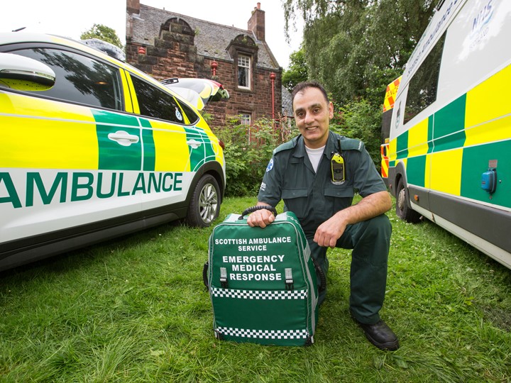 A Paramedic kneels between two ambulance vehicles