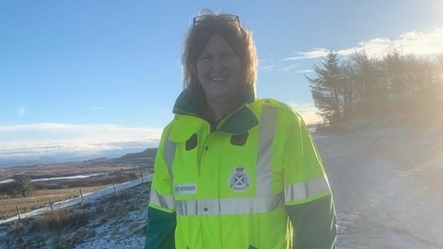 Skye volunteer Bridget Little dressed in high vis jacket standing on a snow covered road.