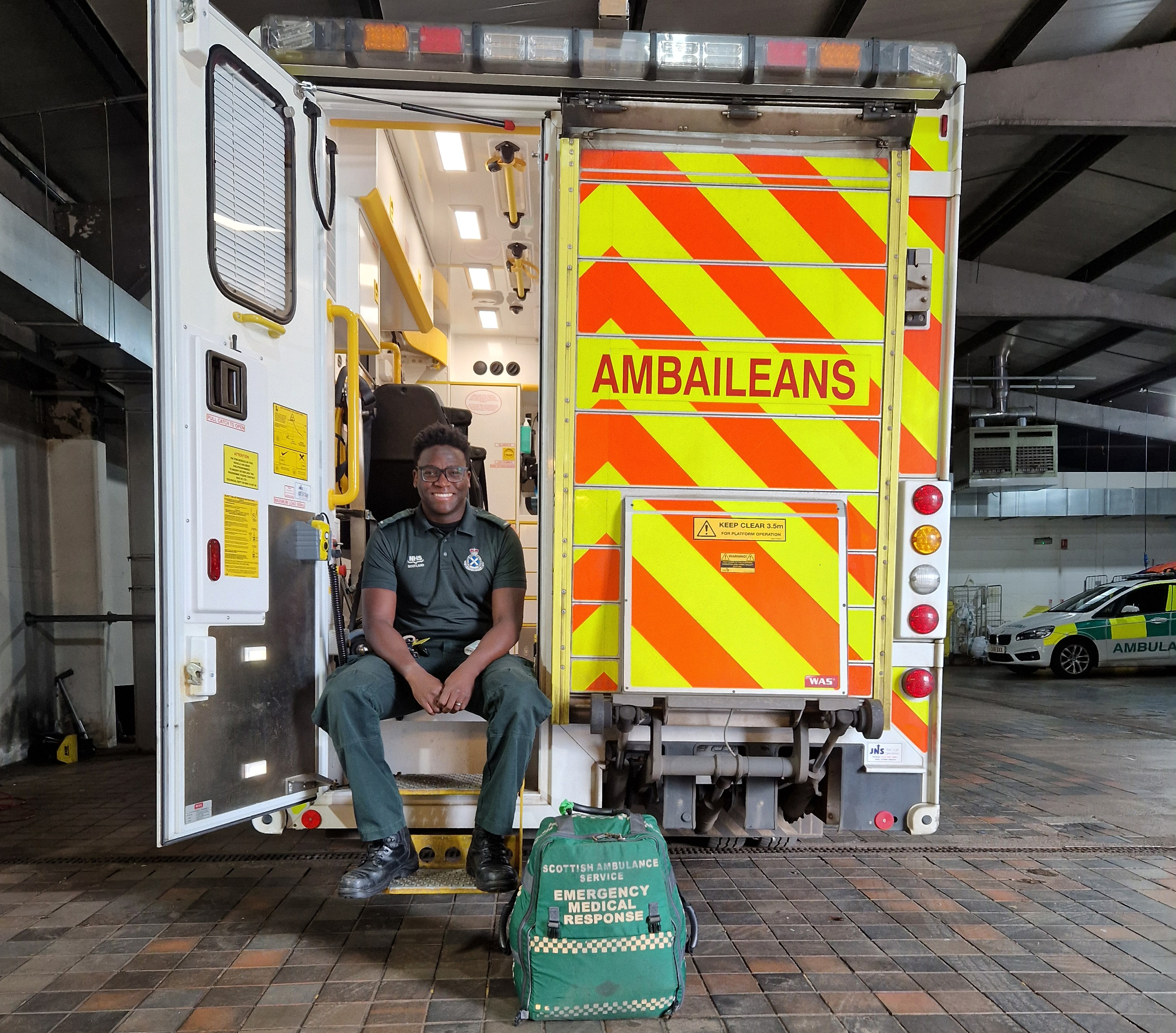 An Ambulance Technician sits on the steps at the back of an A&E ambulance