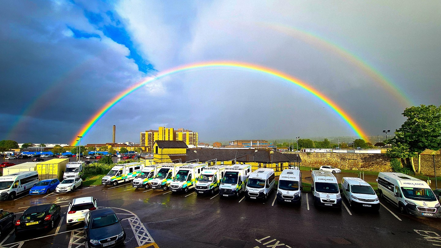 A car park full of ambulances with a rainbow above