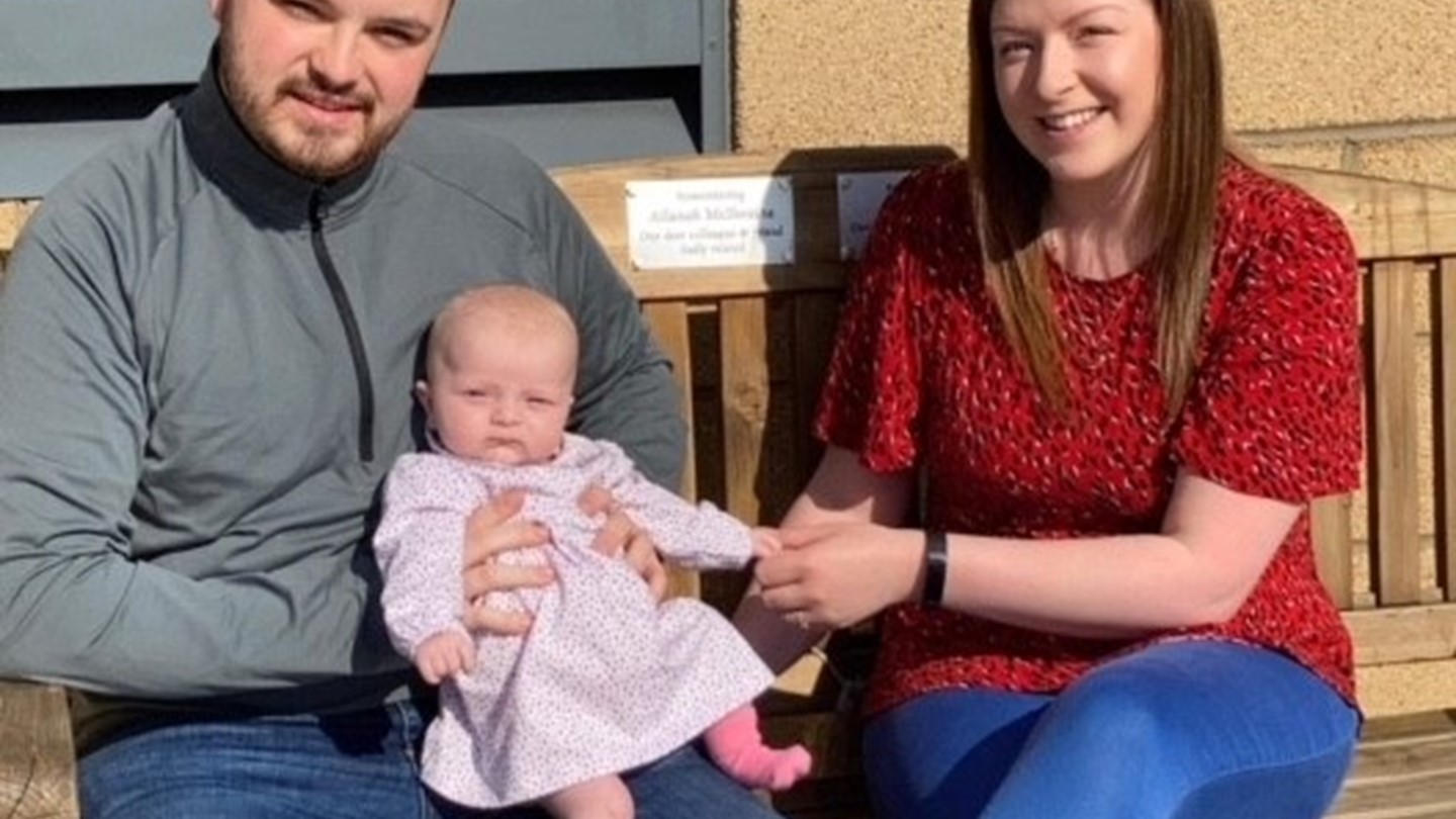 John and Laura, along with their daughter Lana sitting on the bench