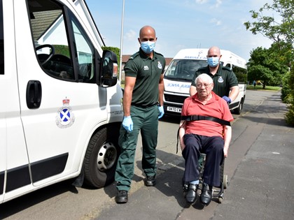 Two Ambulance Care Assistants with a patient next to an ambulance
