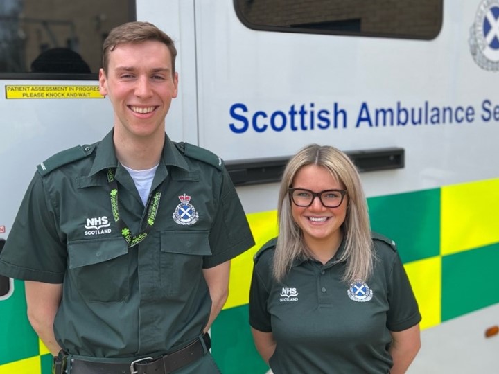 Two members of staff in front of an ambulance