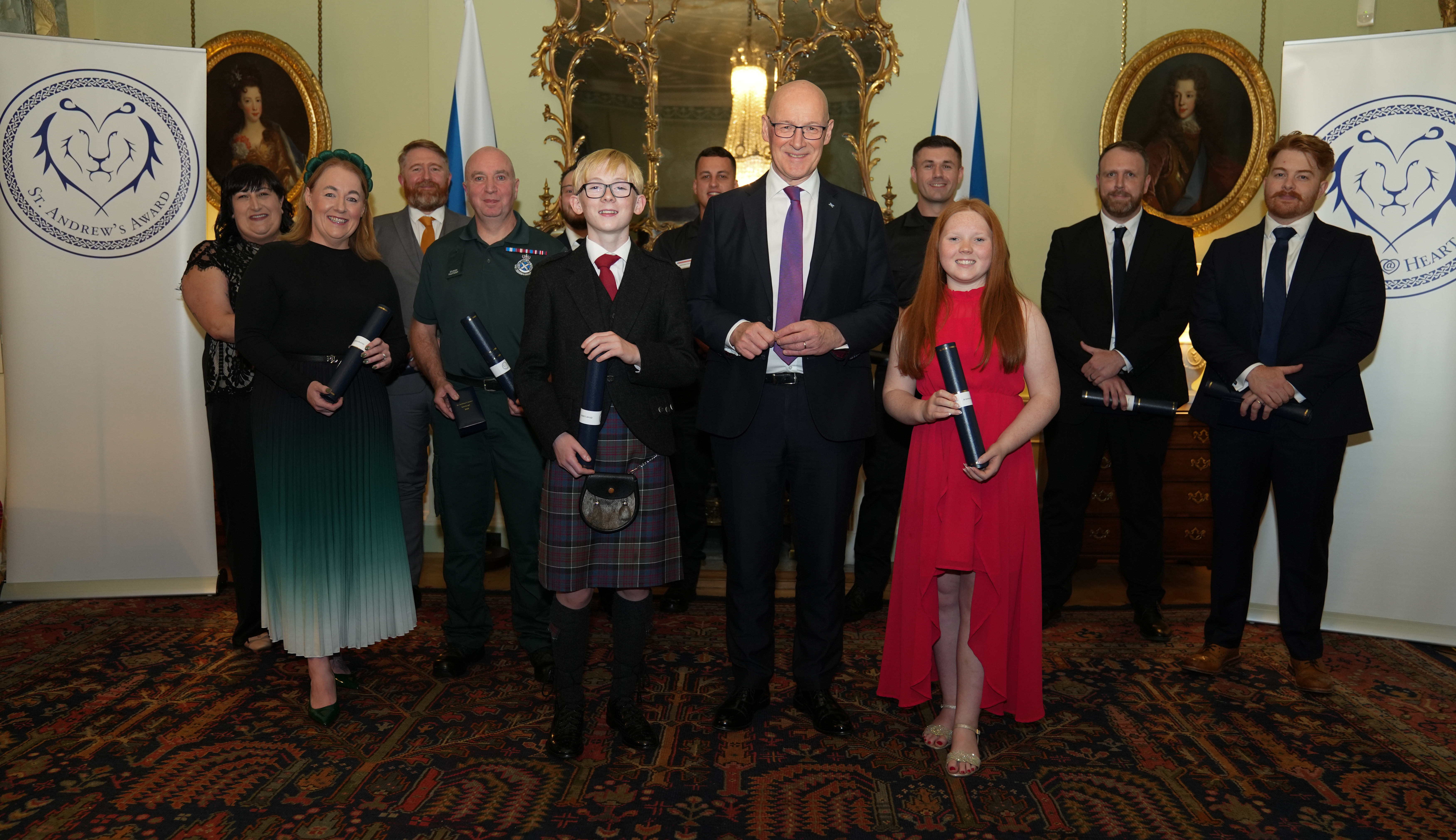 A group of 12 people dressed in black tie attire holding their awards.