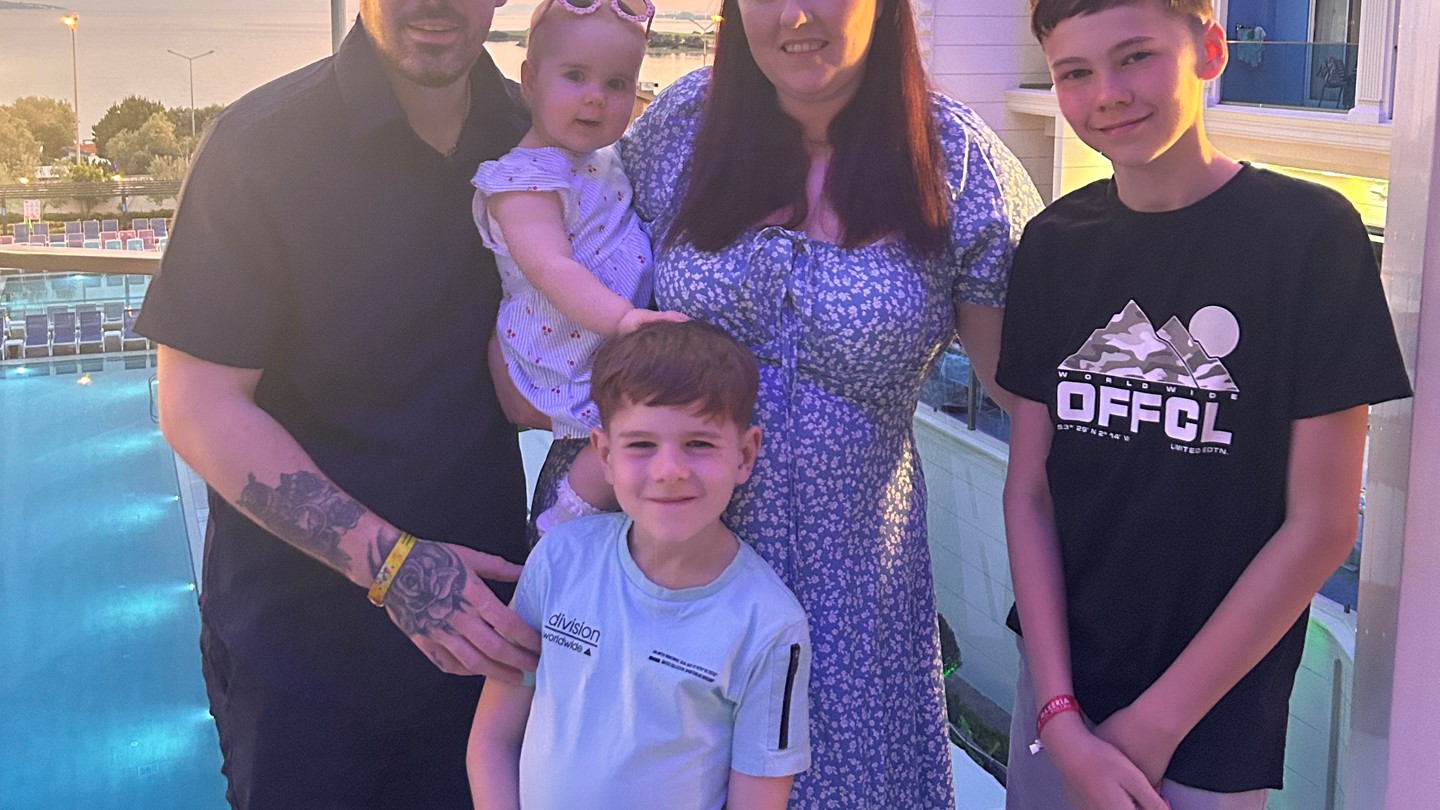 Shannon and her entire family pose for a photo on a holiday. Kids and husband look towards camera with the sun setting in the background