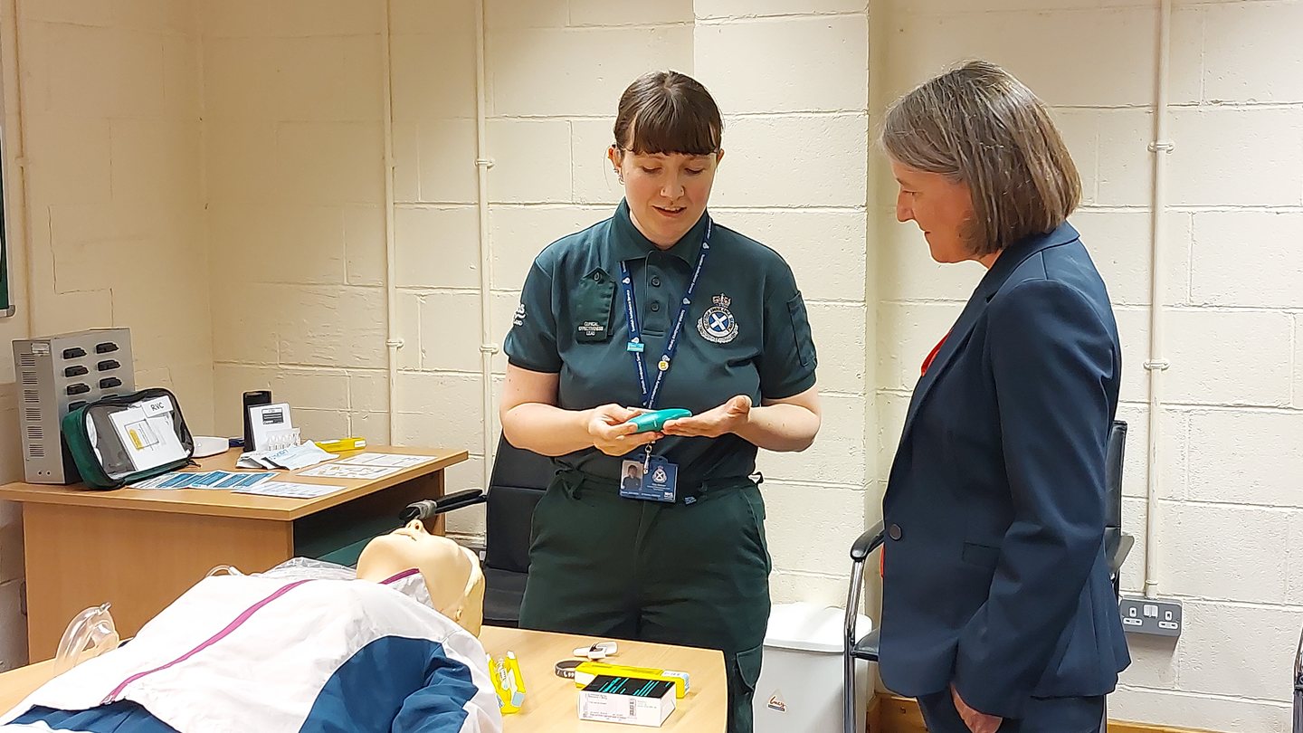SAS staff member demonstrating a nasal naloxone kit to MSP Marie Todd.