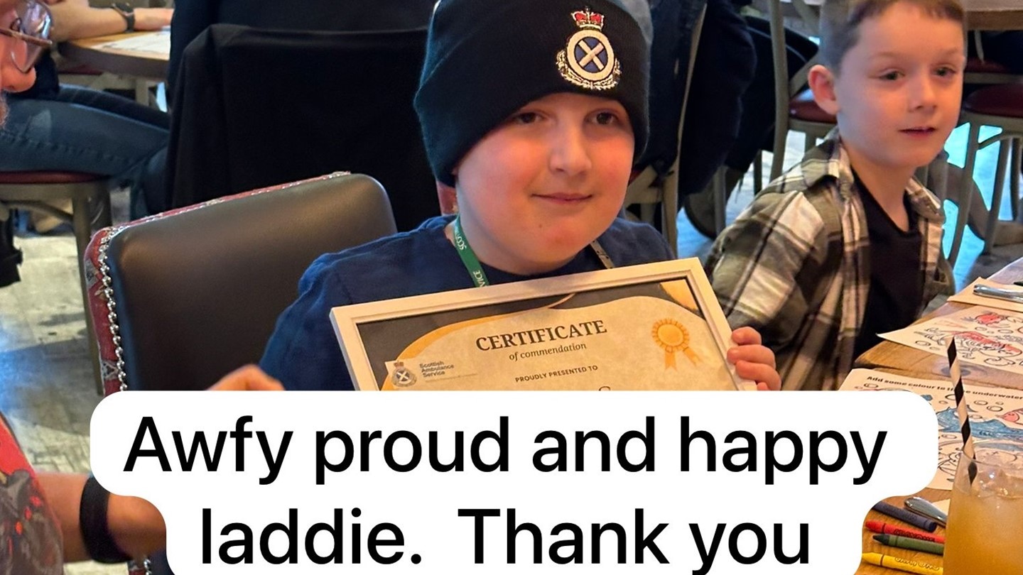 Murray showing his certificate with a sign saying Awfy proud and happy laddie. Thank you