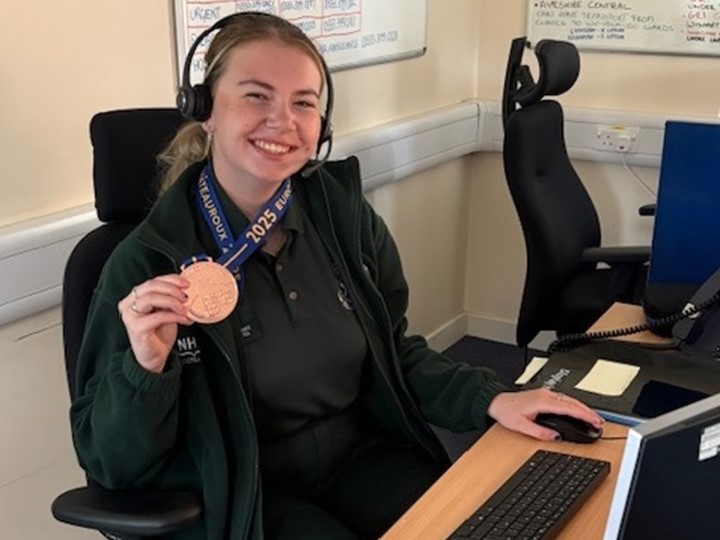 Izzy proudly displays her bronze medal at her computer screen
