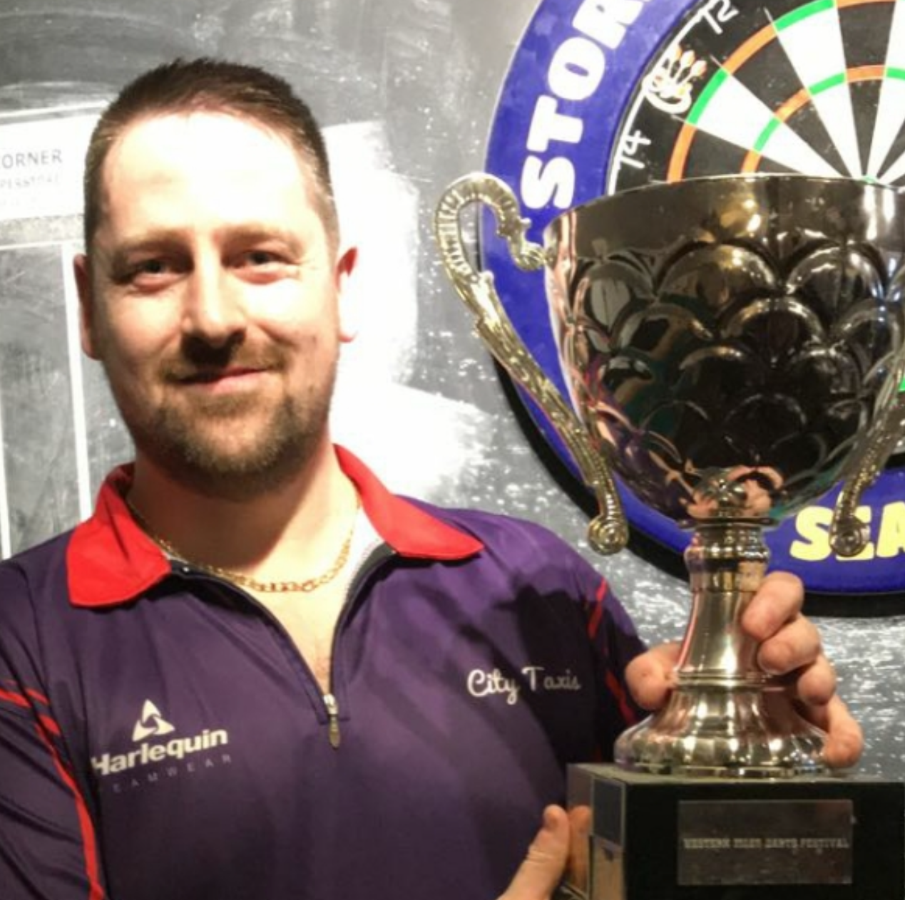 Derek proudly displays a darts trophy after winning