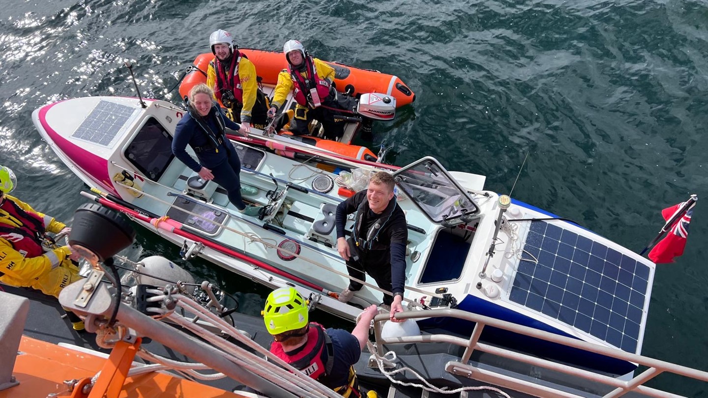 Coastguard staff look up whilst standing on a boat