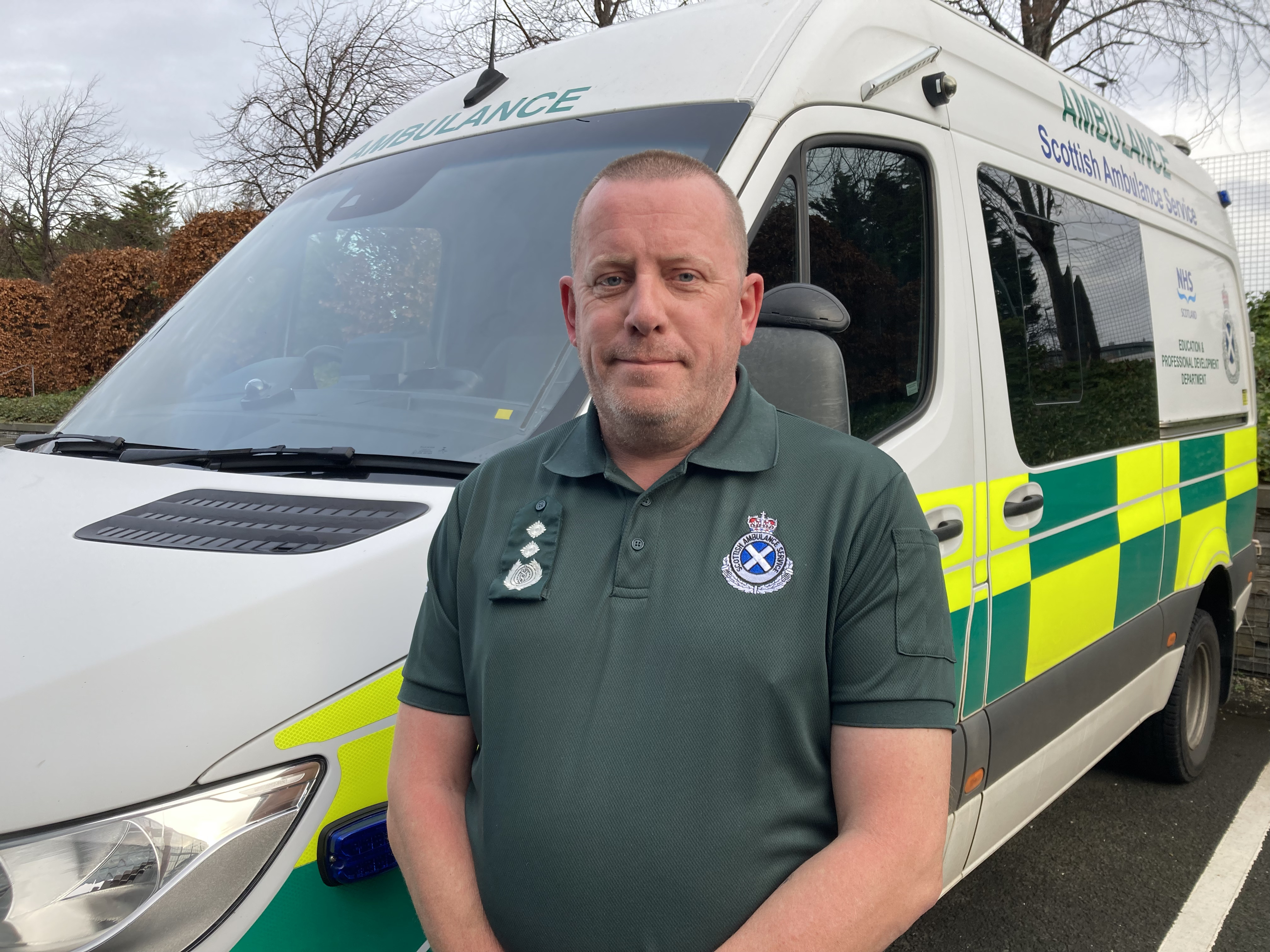 Dave stands in front of an ambulance in uniform