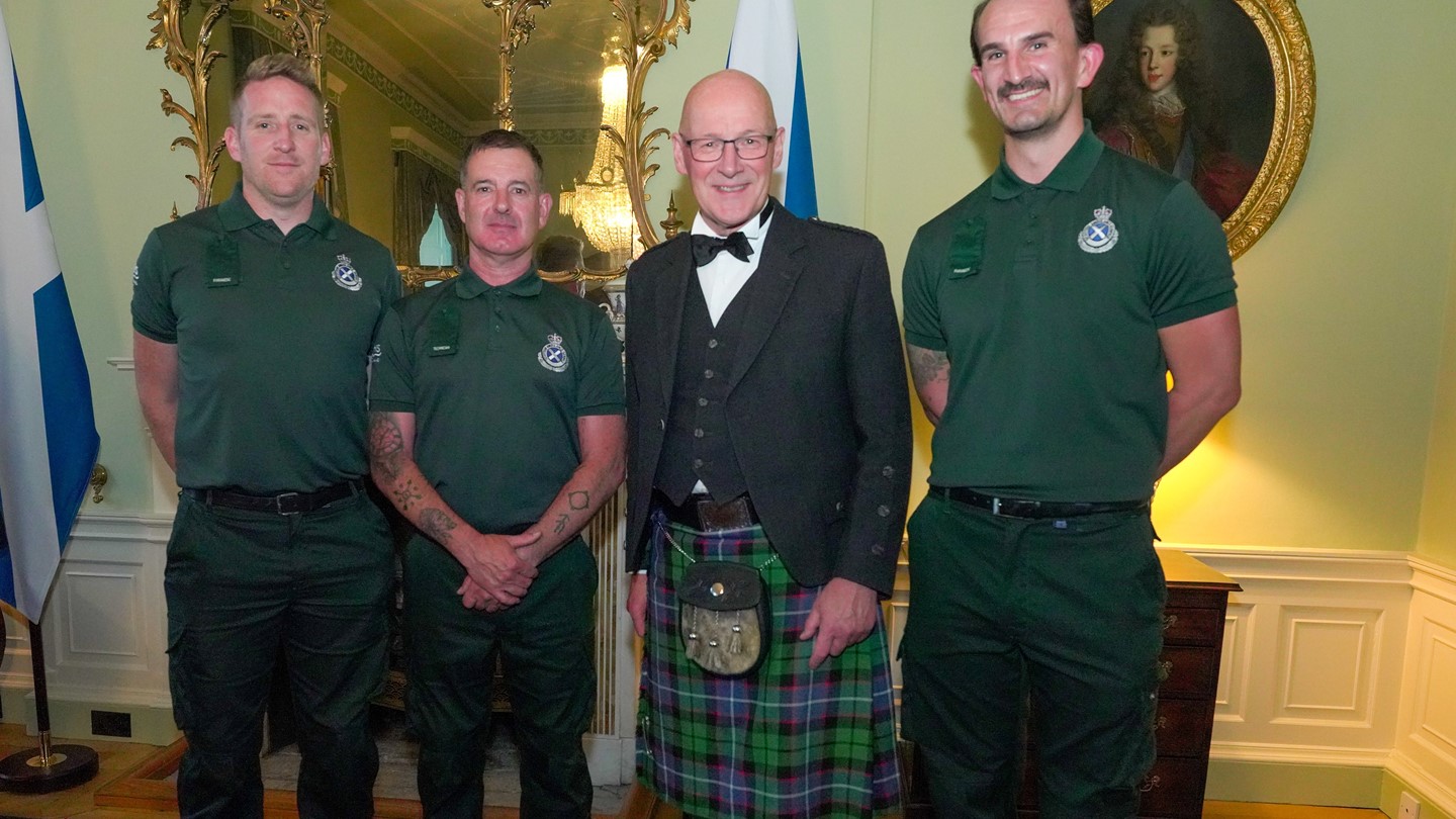 Three SAS emergency response staff stand with First Minister John Swinney