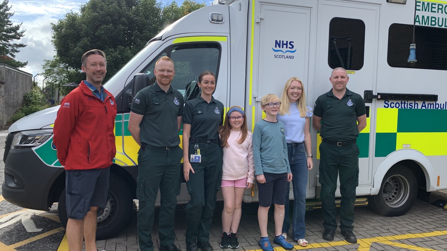 SAS staff members who attended to Donna stand next to the mum and her children in front of an ambulance