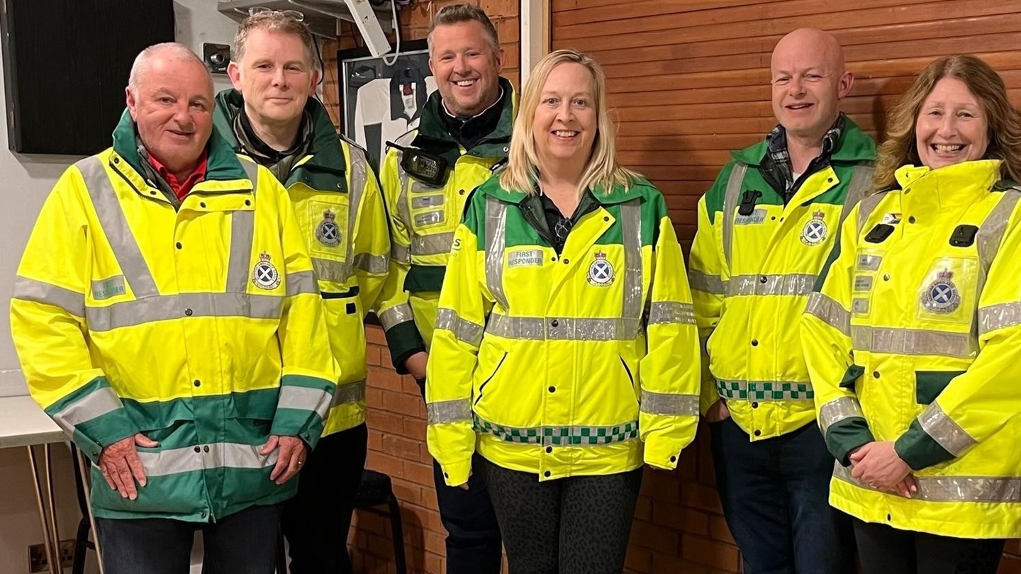 Penicuik Community First Responder Group - 4 men and 2 women are dressed in high vis community first responder jackets stood together and smiling at the camera.