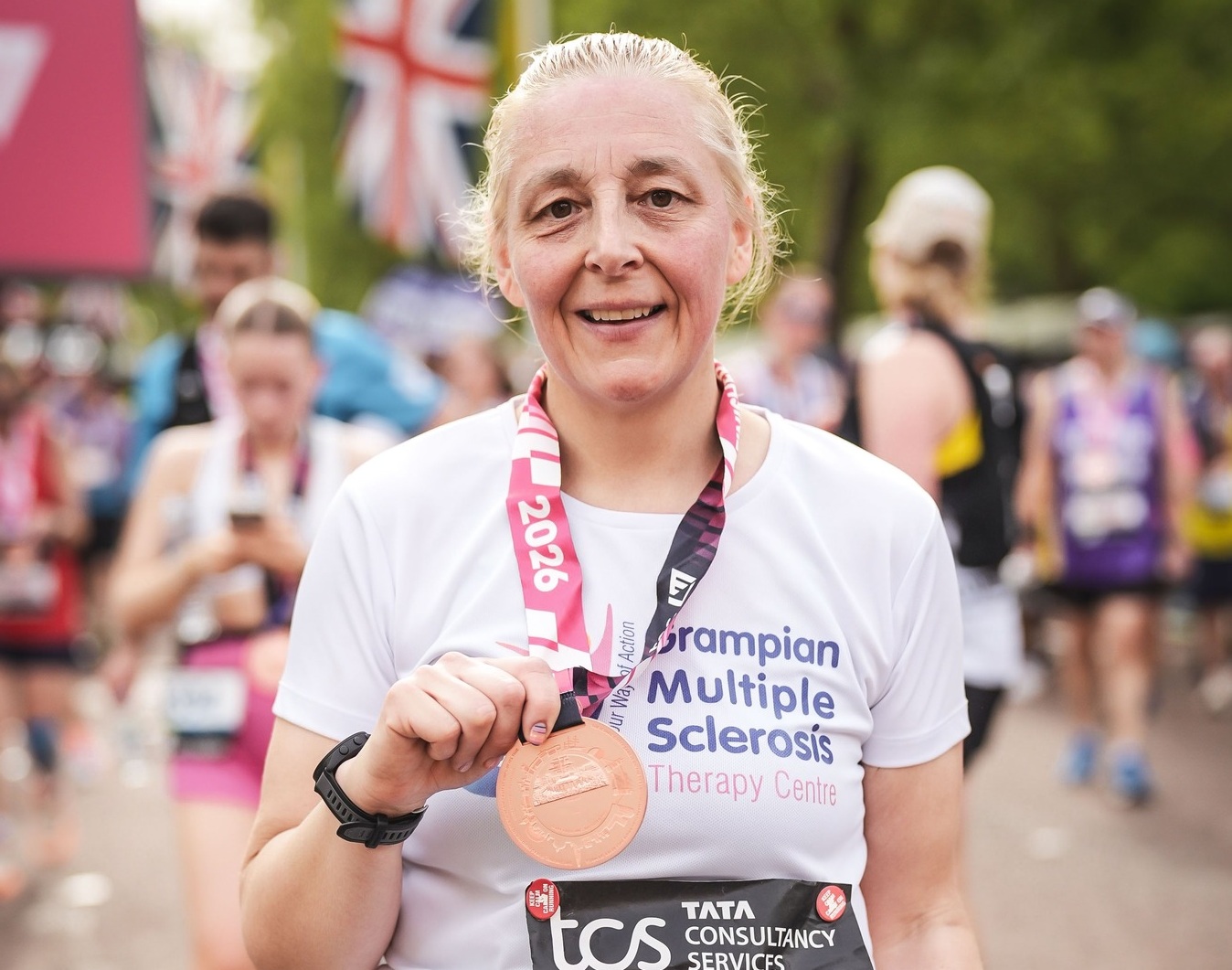 Jenny in her running gear, proudly, displays her medal after completing the marathon