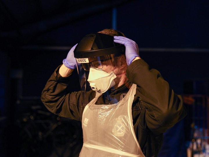 A Scottish Ambulance Service staff member stands ready to attend a job in mask and gloves during Covid