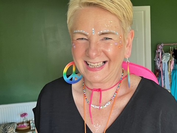 Eileen with a big smile on her face dressed in rainbow apparel