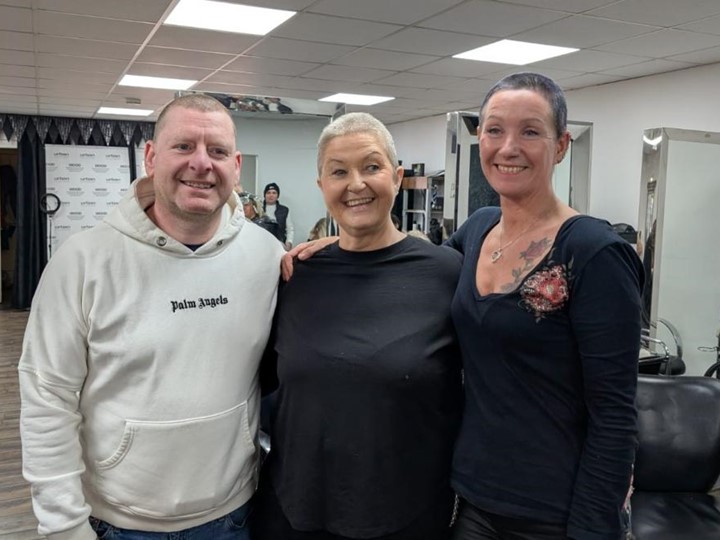 The 3 Scottish Ambulance Service staff members with their hair saved off stand proudly at the hair salon