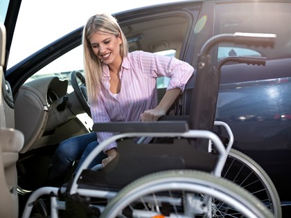 A woman getting out of car into a wheelchair
