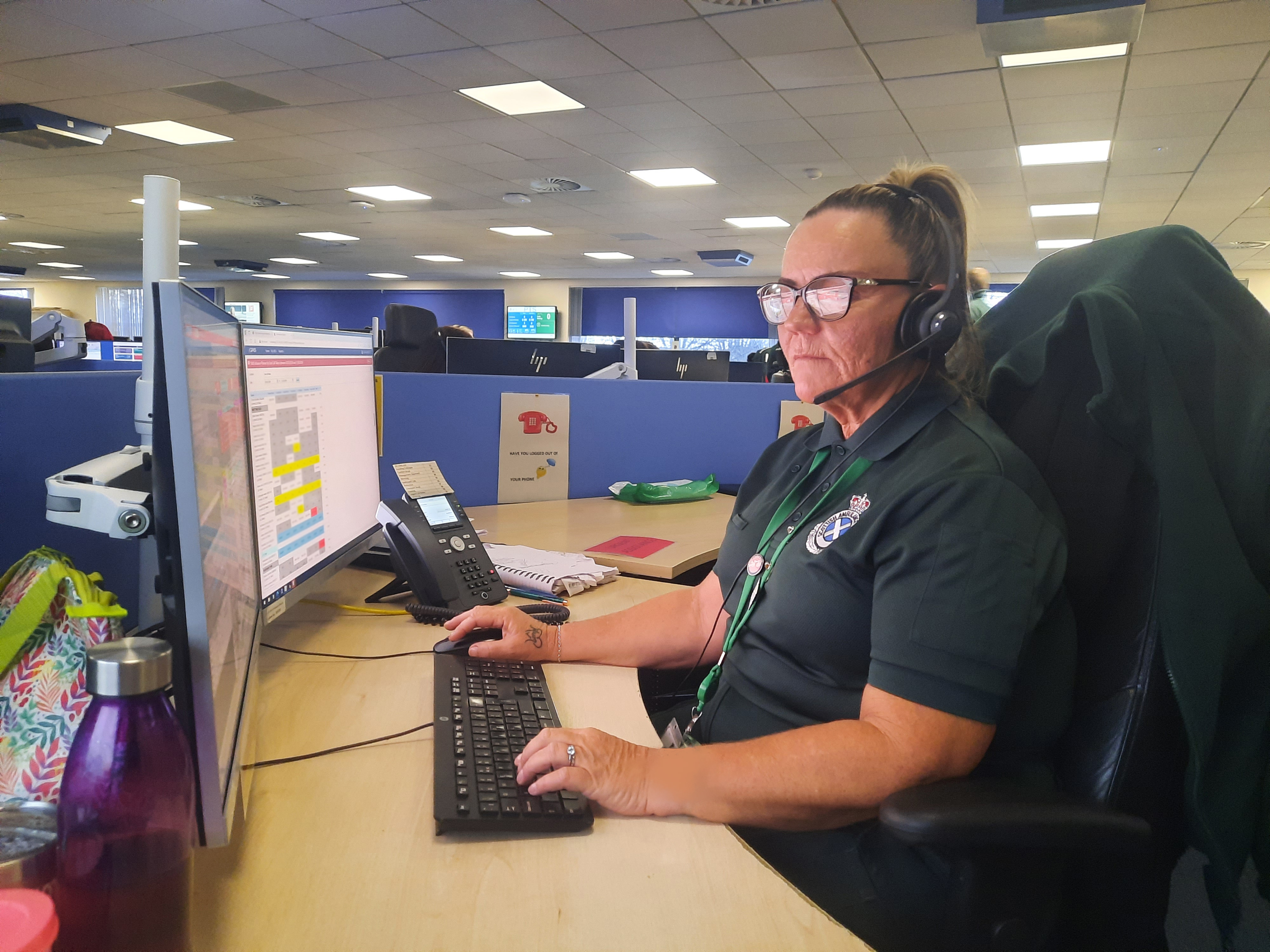 A 999 Call Taker talking to a patient and entering information onto a computer