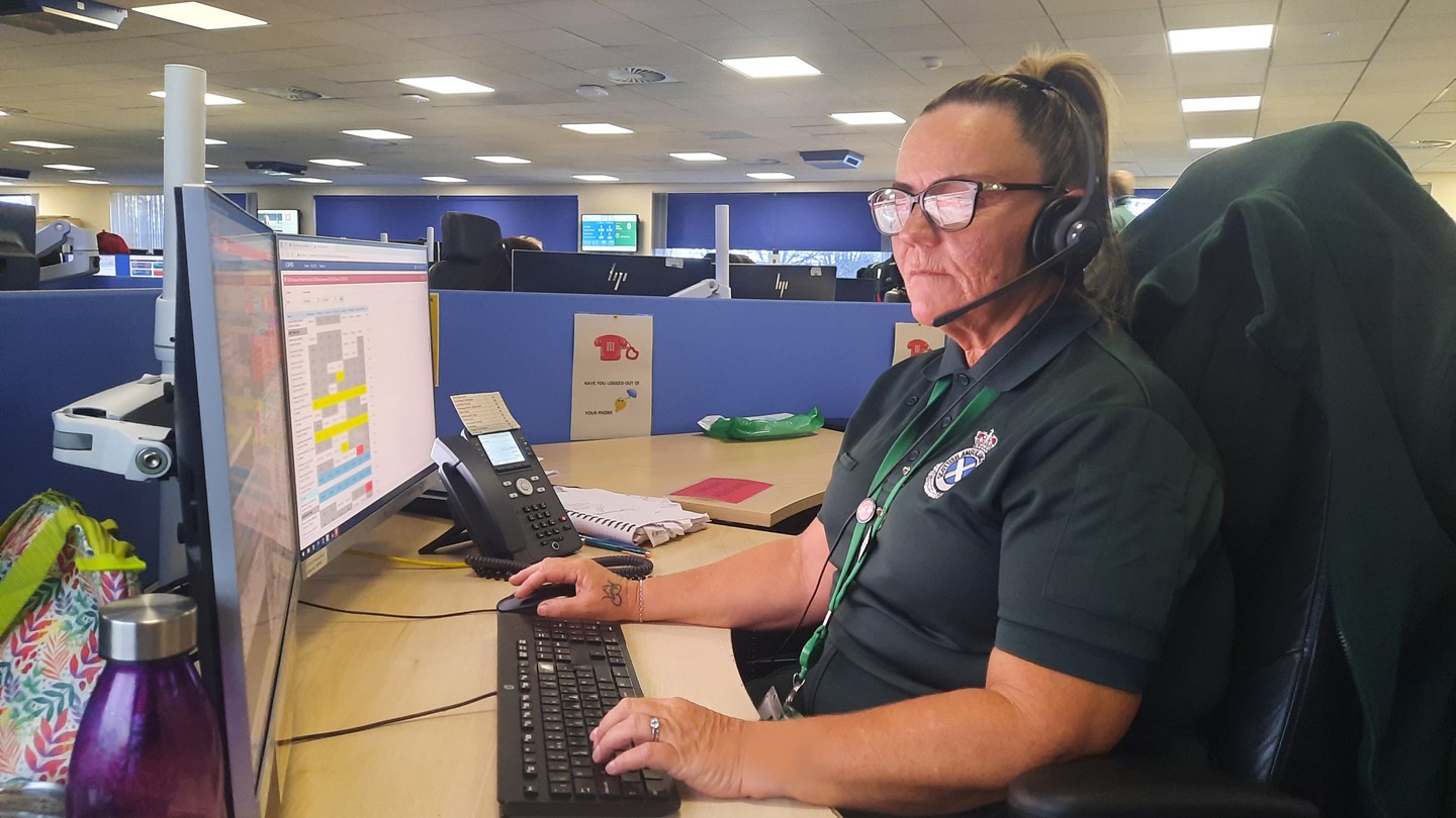 A 999 Call Taker talking to a patient and entering information onto a computer