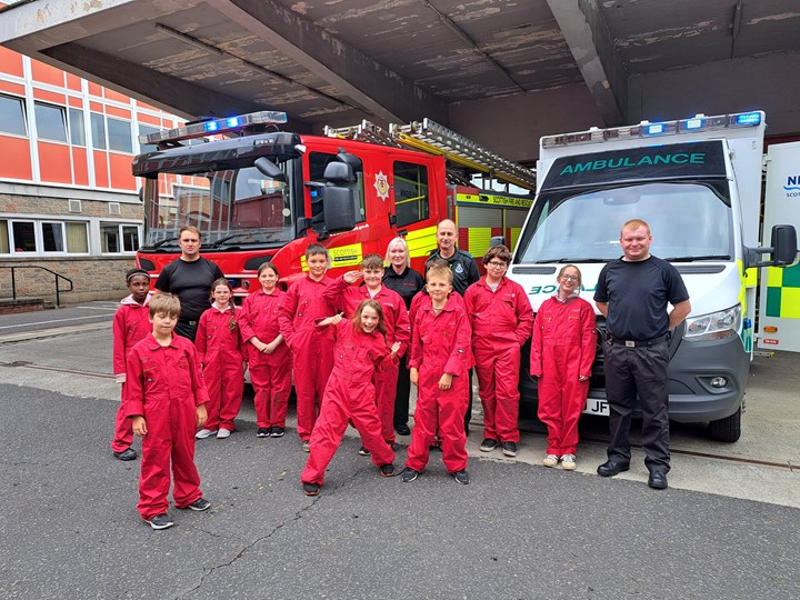 children with ambulance service and fire service staff in front of fire engine and ambulance