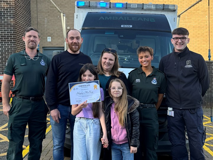 Hayley holds her certificate proud with her sister dad and Scottish Ambulance Service staff who helped