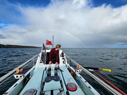 Rowing on open water with rainbow in the background