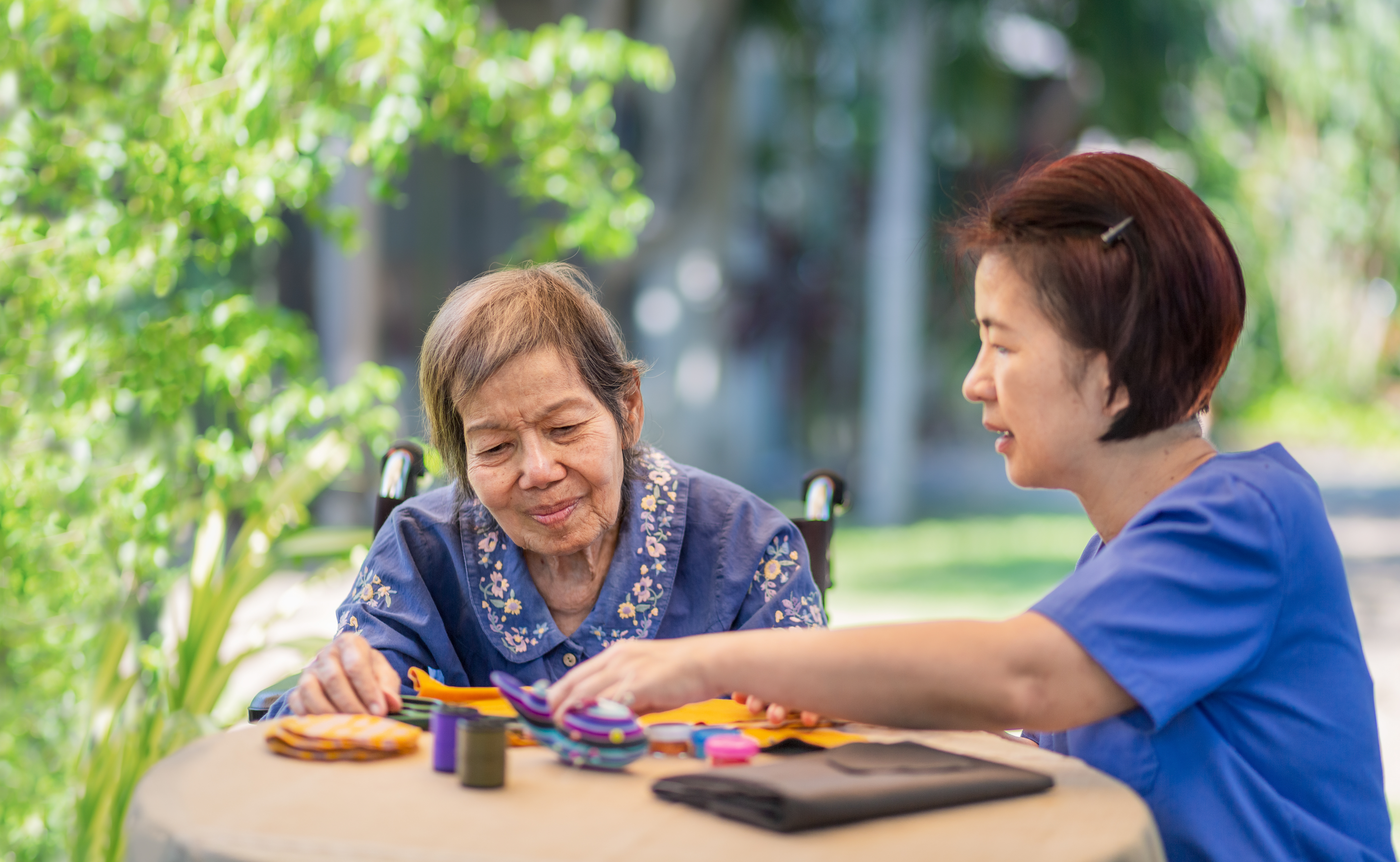 A woman plays a board game with her mum at a table in the garden