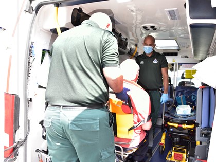 Two ambulance Care Assistants help a patient into an ambulance