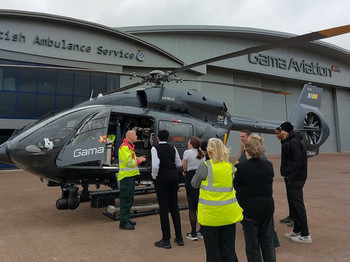 A group of school children listening to ScotStar paramedic who is giving a tour of a grey air ambulance.
