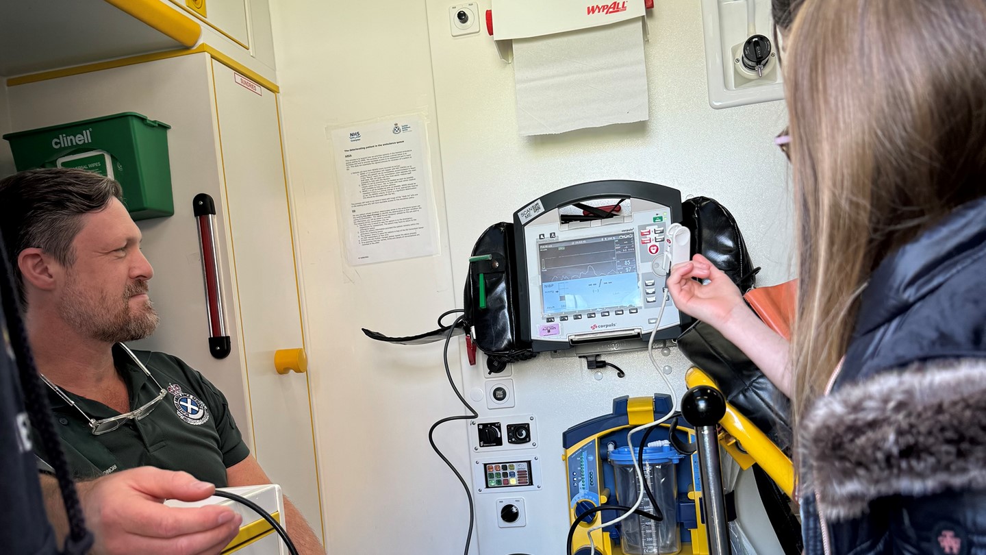 A SAS staff member shows young Hayley how to use a defib in the back of an ambulance