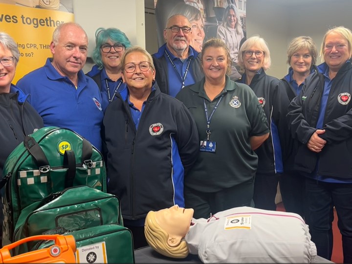 A group of 8 community first responders and one paramedic standing and smiling at the camera.